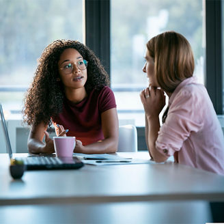 Colleagues talking at work desk