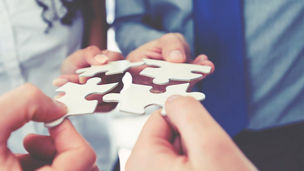Personen fügen Puzzleteile zusammen