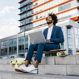 Spain, Barcelona, young businessman sitting outdoors in the city working on laptop
