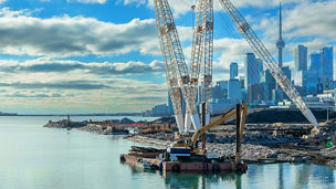 Excavator on a construction barge building a bridge