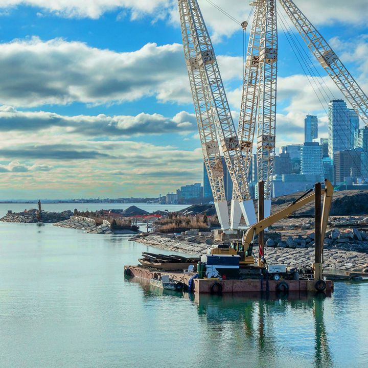 Excavator on a construction barge building a bridge