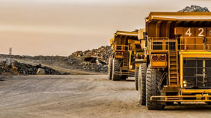 Large construction vehicles parked on a dirt site with earth-moving equipment in an open landscape