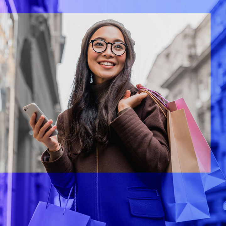 Person holding shopping bags and a phone in a street