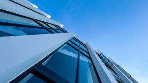corner of the glass building contrasts with the blue sky.