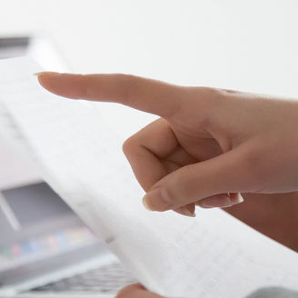 Woman checking paper vs laptop