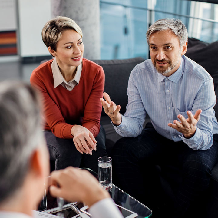 Mid adult man and his wife communicating with financial advisor during consultations in the office.