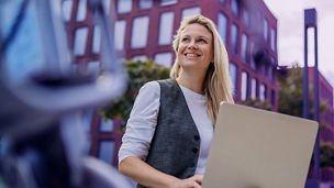 Woman is sitting outside with her laptop on her knees