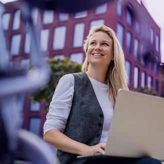 Woman is sitting outside with her laptop on her knees