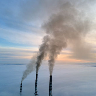 Aerial view of coal power plant high pipes with black smoke moving up polluting atmosphere at sunset.