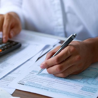 A man is sitting at his desk with papers and a calculator.