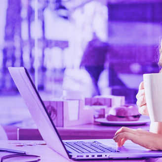 Woman looking at laptop while drinking coffee