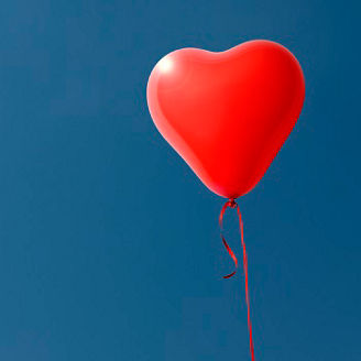 One red heart-shaped balloon floating in a blue sky with copy space.