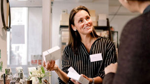 En kvinne illustrerer noe på tavla i et arbeidsmøte med kollegaer.