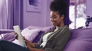 Happy, home and black woman on sofa on tablet for social media, online shopping and internet. Relax, rest and person on digital tech for reading website, news and research on weekend in living room.