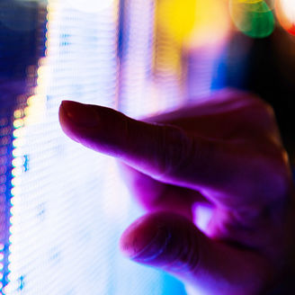 Man finger pointing at LED screen of stock market price at night.