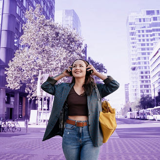 Smiling woman listening to music through wireless headphones in city