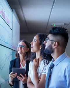 Three cyber security professionals look at large screen