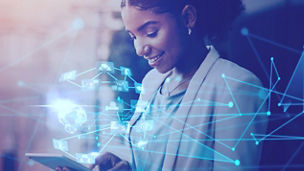 Mulher a sorrir enquanto utiliza um tablet, com elementos gráficos digitais e ligações em rede sobrepostos, representando tecnologia, inovação e conectividade.