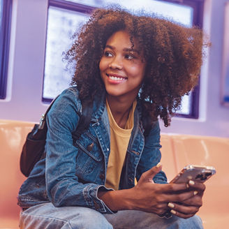 Happy young African American woman passenger smile and using smart mobile phone in subway train station; Shutterstock ID 2284445297; purchase_order: marketing advisory assurance; job: anne rouschop; client: artificial intelligence