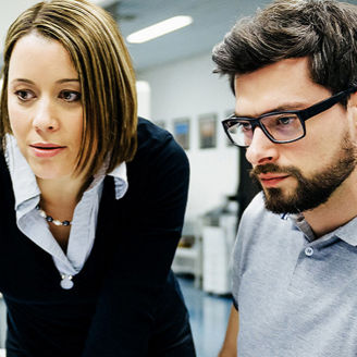 Zwei Personen arbeiten vor einem Bildschirm