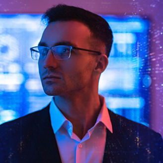Close-up of a man in a suit wearing glasses, facing slightly to the side, with a blurred background of blue and purple digital lights and abstract patterns