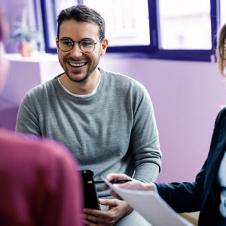 Happy businessman sitting with colleagues in office; Shutterstock ID 2508967317; purchase_order: marketing; job: anne; client: merkcampagne