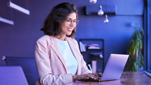 Mulher sorridente a escrever num portátil em ambiente de escritório