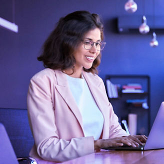 Mulher sorridente a escrever num portátil em ambiente de escritório