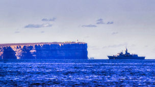 Sea horizon with HMAS frigate marching at military navy exercise in Jervis Bay in Australia.
