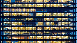 Workers working late. Office windows by night.