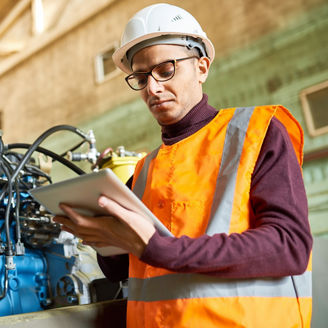 Waist up portrait of middle eastern factory worker using digital tablet standing by power units, copy space