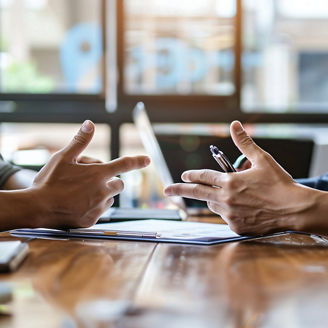 Two people having a discussion at a table with focus on their hands