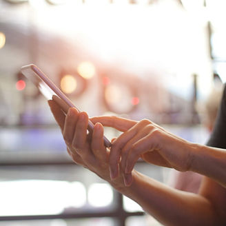 Close up of women's hands holding smartphone. Her watching sms, message, e-mail on mobile phone in coffee shop. Blurred background.