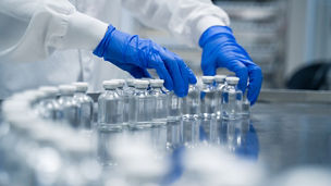 Detail of hands working in pharmaceutical factory manufacturing sterile bottles