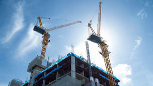 Silhouette Construction site background. Hoisting cranes and new multi-storey buildings. Industrial background. Building construction site work against blue sky.