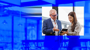 Two people looking at a tablet together in an office setting, shown with a blue overlay
