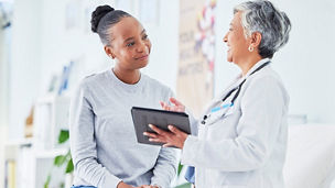 Doctor holding a tablet taking to patient