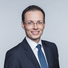 Porträt von Dominik Zacherl vor einer hellgrauen Wand