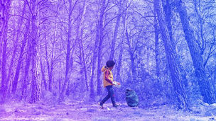 Black child picking up a plastic bottle from the forest to recycle