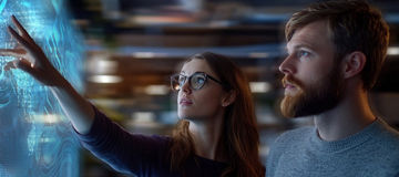  two people infront of digital board