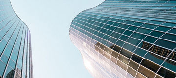 Low angle view of a curved building with glass and steel facade in Barcelona, Spain.