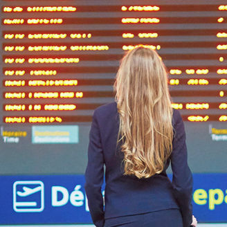 Frau steht vor Abflugstafel