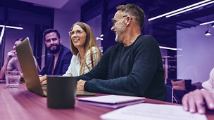 Successful group of businesspeople having a briefing in a boardroom. Happy businesspeople smiling while working together in a modern workplace. Diverse business colleagues collaborating on a project.; Shutterstock ID 2112192335; purchase_order: Team Advisory Assurance; job: Anne Rouschop; client: AI campagne