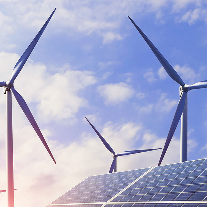 Solarmodule und Windräder unter blauem Himmel – erneuerbare Energien.