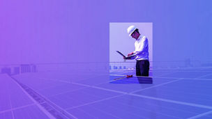 Man kijkt op zijn laptop terwijl hij tussen zonnepanelen staat