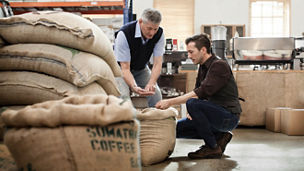 Male owner of a coffee roasting business talking with worker