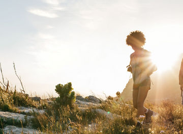 Group of friends are hiking in mountain on a sunny day. Young people walking through countryside.