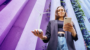 vrouw met windmolen beeldje in haar rechterhand en telefoon aan haar linkerhand