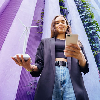 Woman holding a small windmill figurine in her right hand and a phone in her left hand.