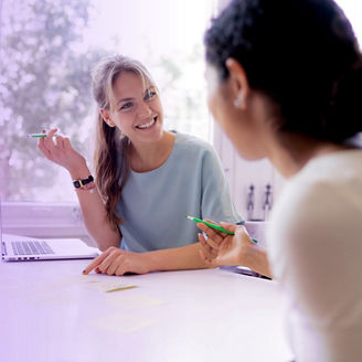 Twee vrouwen die naar elkaar lachen en werken